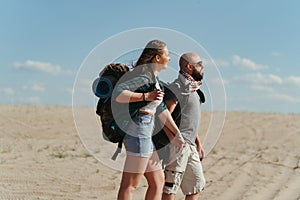 Couple with backpacks walking in the desert.