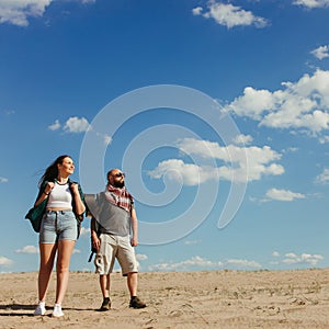 Couple with backpacks walking in the desert.