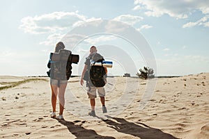 Couple with backpacks walking in the desert.