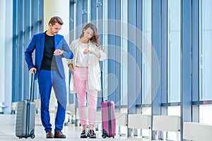 Couple with baggage in international airport hurrying for a flight to land. Man and woman looking on their clock indoor