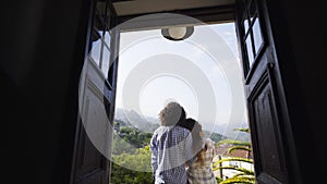 Couple on balcony of villa between hills in village