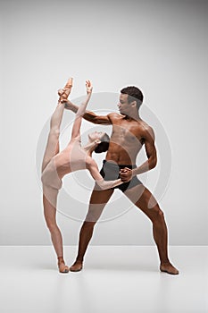 Couple of ballet dancers posing over gray background