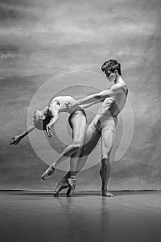 Couple of ballet dancers posing over gray background