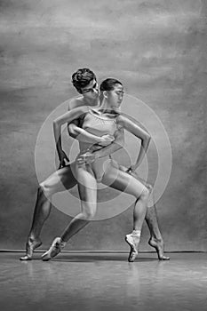 Couple of ballet dancers posing over gray background