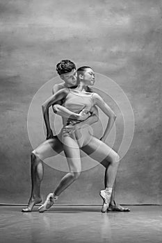 Couple of ballet dancers posing over gray background