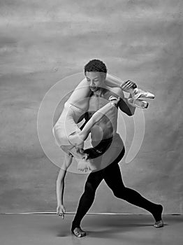 Couple of ballet dancers posing over gray background