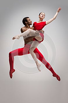 Couple of ballet dancers posing over gray background