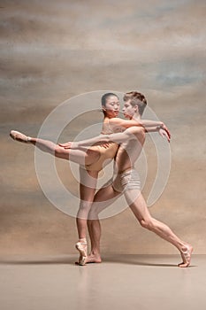 Couple of ballet dancers posing over gray background