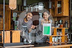 a couple of barista pointing on the digital tablet with green screen