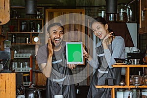 a couple of barista smiling while showing the digital tablet