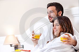 Couple in bathrobe drinking orange juice.