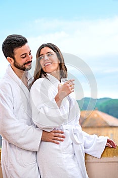 Couple in bathrobe standing on hotel balcony.