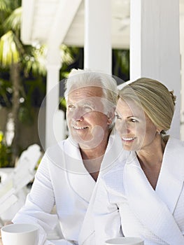 Couple In Bathrobes With Cups On Verandah