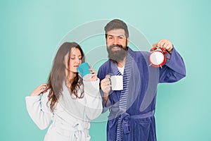 Couple in bathrobes with mugs. Man with beard and sleepy woman enjoy morning coffee or tea. Time to wake up and have