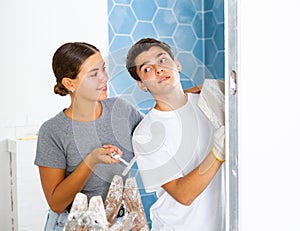 Couple in the bathroom glues ceramic tiles on the wall