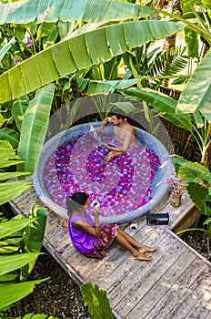 Couple at a bathtub in the rainforest of Thailand during vacation with flowers in the bath