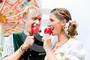 Couple in Bavarian clothes eating candy apples