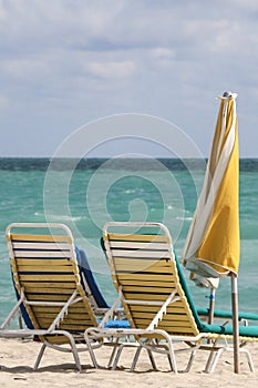 A couple of beach chairs and yellow umbrela in Miami beach