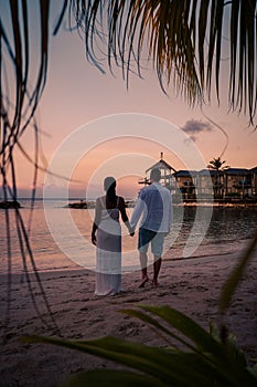 Couple on the beach of Curacao during sunset, men and woman watching sunset on the tropical beach of Curacao