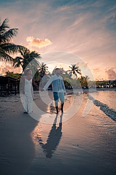 Couple on the beach of Curacao during sunset, men and woman watching sunset on the tropical beach of Curacao