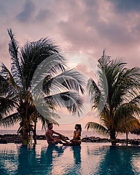 Couple on the beach of Curacao during sunset, men and woman watching sunset on the tropical beach of Curacao