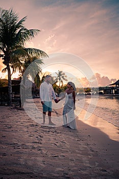 Couple on the beach of Curacao during sunset, men and woman watching sunset on the tropical beach of Curacao