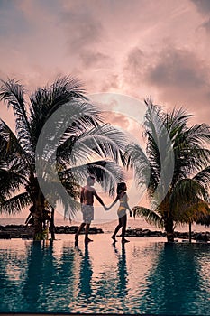 Couple on the beach of Curacao during sunset, men and woman watching sunset on the tropical beach of Curacao