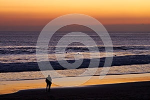 Couple at beach by dusk watching surfers