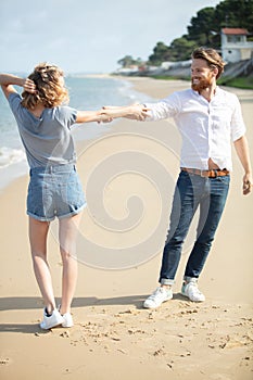 couple on beach with interlinked arms photo