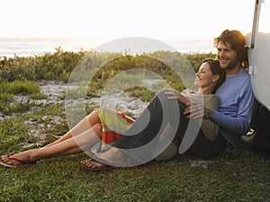 Couple On Beach Leaning On Campervan