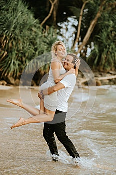 Couple on the beach. A man holds a girl in his arms.