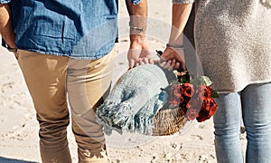 Couple, beach and picnic basket with flowers in walking, back and holiday for vacation, ocean and cropped shot. Romantic