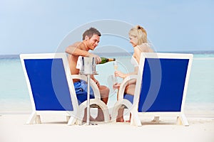 Couple On Beach Relaxing In Chairs And Drinking Champagne