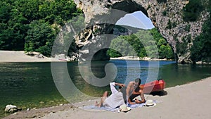 Couple on the beach by the river in the Ardeche France Pont d Arc, Ardeche France,view of Narural arch in Vallon Pont D