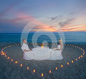 Couple at beach romantic dinner with candles heart