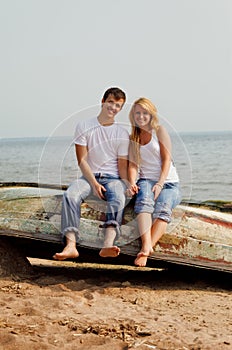 Couple on a beach sitting on old boat