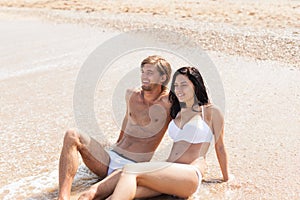 Couple on beach, sitting in water embrace