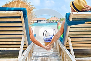 Couple at beach on wooden sun bed loungers