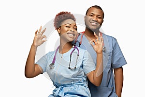 Couple of beautiful african-american doctors or nurses smiling isolated over white studio background