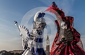 Couple with beautiful costume and venetian mask during venice carnival with campanile in the background