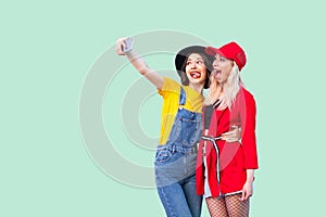 Couple of beautiful stilysh hipster best friends in fashionable clothes hugging with love, posing for camera and making selfie or
