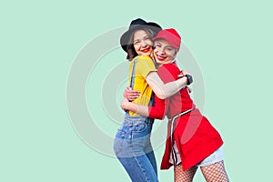 Couple of beautiful stilysh hipster best friends in fashionable clothes standing, hugging with love, glad to see each other,