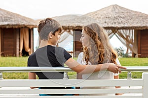 Couple of beautiful teens, first love. Guy hugs a girl sitting on a bench and looking to each other