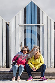 Couple of beautiful women on vacation relaxing in front of a beach cabin