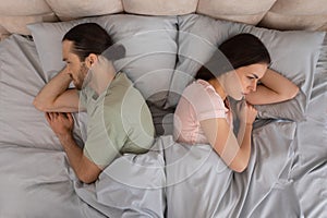 Couple in bed facing away from each other, upset