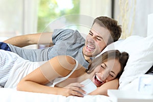 Couple on bed laughing watching phone content