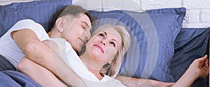 Couple in bed. Man and woman are enjoying spending time together while lying in bed. Happy middle aged couple in bedroom