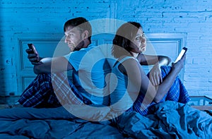 Couple in bed on mobile phones ignoring each other in relationship problems and technology addiction