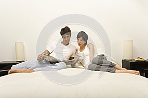 Couple on bed reading newspaper
