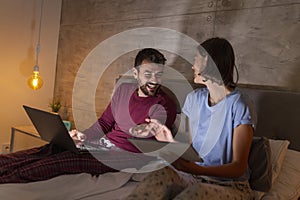 Couple in bed searching for vacation ideas